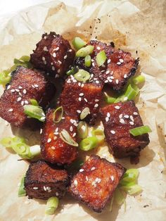 some food that is sitting on top of a piece of wax paper with sesame seeds