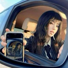 a woman taking a selfie with her cell phone in the back seat of a car