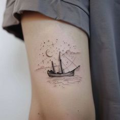 a small ship tattoo on the right side of the thigh, with stars and moon in the sky