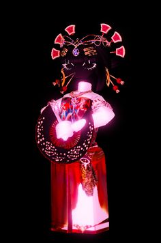 a woman wearing a costume and holding a fan in her hand with lights on it