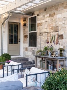 the front porch is decorated with potted plants and outdoor furniture, including sofas