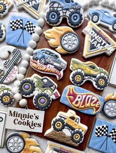 decorated cookies with cars and trucks are displayed on a table in front of a sign that says minee's cookies