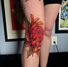 a woman's legs with tattoos and flowers on the thighs, both decorated in red