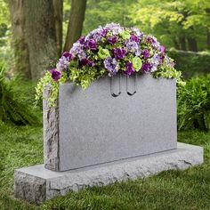 a stone bench with flowers on it in the grass