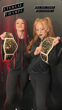 two women standing next to each other holding up their wrestling belts