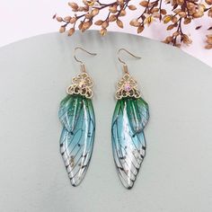 a pair of earrings with blue and green wings