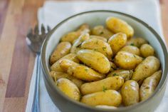 a bowl filled with potatoes sitting on top of a table next to a knife and fork