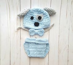 a crocheted blue dog hat and diaper cover on a white wooden background