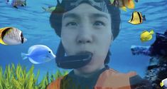 an underwater scene with fish and a young man wearing a snorkels mask