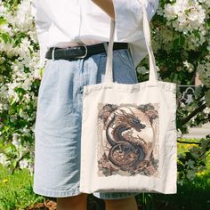 Elevate your style with our Floral Dragon Tote Bag! 🐉🌸 Embrace sustainability with this 100% cotton canvas shopping tote, a perfect gift for him or her, and a delightful surprise for kids. Immerse yourself in vintage art inspired by Chinese and Japanese cultures. Our eco-conscious tote is a timeless addition to your collection--a practical yet stylish statement with a touch of dragon magic. Shop now for a unique, nature-inspired accessory.  🎁 ☼ Applications:  ▸ | Shopping bag | perfect for everyday wear | ▸ | nature | beach | outdoors | home living | ☼ Material:  ▸ 100% pure cotton ⋆｡˚. ▸ Heavy fabric (12 oz/yd² (406.9 g/m ▸ Sewn-in label ▸ Durable & will last for years ☼ Sizes: ▸ 15 x 16 inch (38cm * 40.6cm) ▸ Handle length 20 inch (50.8cm) ☼ Washing recommendations:  ▸ tumble dry: low Floral Dragon, Dragon Magic, Dragon Lover, Unique Nature, Magic Shop, Chinese Dragon, Perfect Gift For Him, Shopping Tote Bag, Bag Vintage