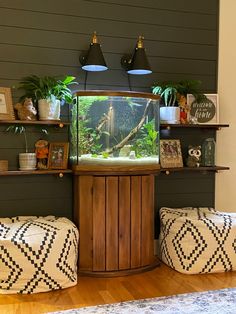 a fish tank sitting on top of a wooden cabinet in a living room next to two ottomans