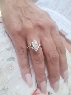 a woman's hand with a diamond ring on top of her finger and the other hand holding an engagement ring