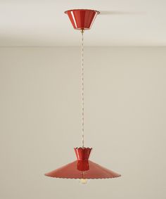 a red light hanging from a ceiling in a room with a white wall behind it