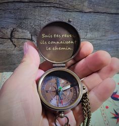 a person holding a compass in their hand with writing on the front and back of it