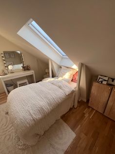 an attic bedroom with white bedding and wooden floors