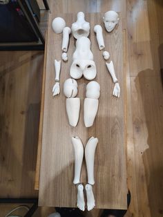 a wooden table topped with white plastic mannequins on top of wood flooring