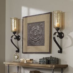 two wall sconces are mounted on the wall next to a table and shelf