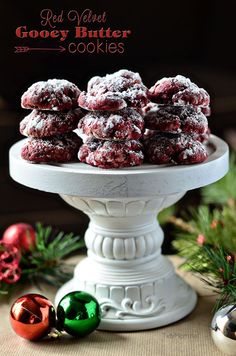 red velvet gooey butter cookies on a white pedestal with christmas ornaments in the background