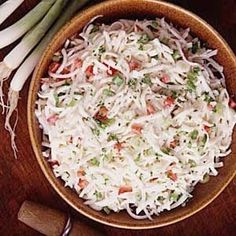 a wooden bowl filled with coleslaw next to onions and celery stalks