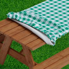 a green and white checkered tablecloth on a picnic bench with wooden slats