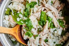 a wooden spoon is in a bowl filled with rice and cilantro