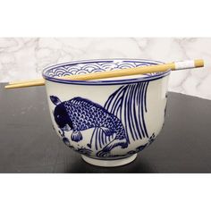 a blue and white bowl with chopsticks in it on a table next to a marble wall