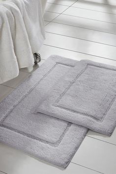 two bath mats sitting on top of a white floor next to each other in a bathroom