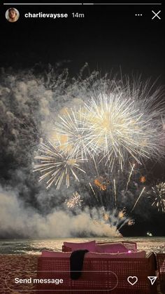 fireworks are lit up in the night sky above a beach with red chairs and tables