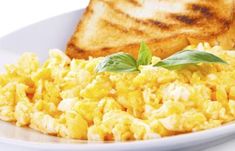 scrambled eggs and toast on a plate with green leafy garnish, ready to be eaten