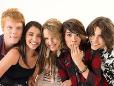 four young people are posing together for a photo in front of a white background and one is holding her hand to her mouth