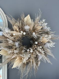 a wreath is hanging on the wall next to a mirror with an ornament