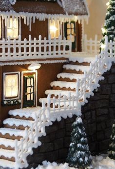 a gingerbread house with snow on the roof and steps to it, decorated with icing