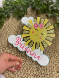 a hand is holding up a paper sun brooch with the word brunch on it