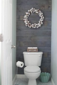 a white toilet sitting in a bathroom next to a wall with a wreath on it