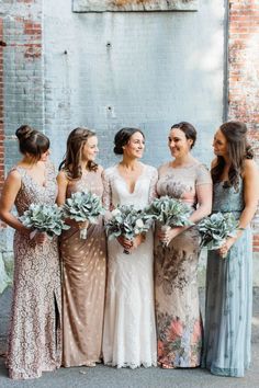 a group of women standing next to each other wearing dresses and holding bouquets in their hands