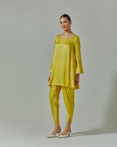 Our Misted Yellow suit set is presented in a soothing shade of yellow. This festive garment was handcrafted from soft modal satin. Delicate cutdana, beaded and zari work at the yoke and cuffs enhance its appeal. It is paired with a tonal embroidered net dupatta to enhance its appeal. For a more dramatic look, choose a pair of dhoti pants to go with the set Color : Yellow Fabric : Modal satin and meshCare : Dry clean onlyFit : Flared The model wears size S. Yellow Suit, Dhoti Pants, Zari Work, Net Dupatta, Dramatic Look, Yellow Fabric, Pakistani Outfits, Suit Set, Shades Of Yellow