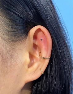 a close up of a person's ear with a piercing on it and a blue sky in the background