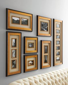 a white couch sitting in front of a wall with framed pictures on it's sides