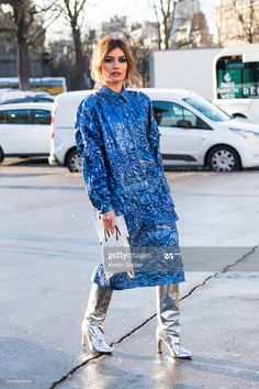 a woman in blue dress and silver boots is seen on the street