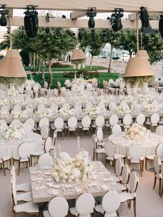 the tables are set with white linens and centerpieces for an outdoor event