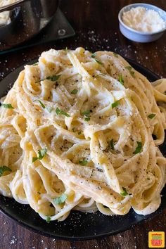 a black plate topped with pasta and parmesan cheese