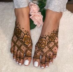 a woman's feet with hennap and flowers on top of her toes