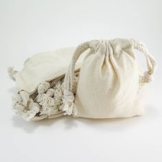 two white bags sitting next to each other on top of a white surface with one bag in the middle