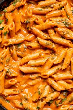 a pan filled with pasta covered in sauce and garnished with fresh parsley