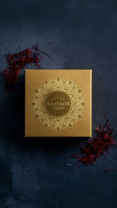 the saffron incense box sits on a blue surface next to dried red flowers