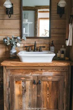 a bathroom sink sitting under a mirror next to a wooden cabinet with drawers and doors