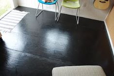 two chairs and a table in a room with black wood flooring on the walls