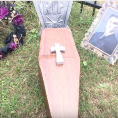 a wooden cross sitting on top of a grave in the grass next to purple flowers