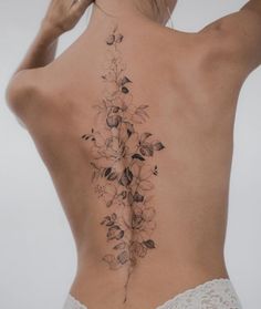 a woman's back tattoo with flowers and leaves on her left side ribcage