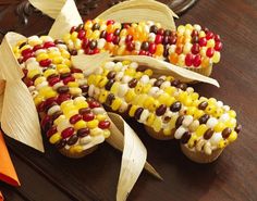 corn on the cob is decorated with candy and other toppings, along with an orange napkin